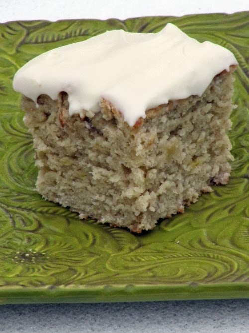 Old fashioned classic banana cake with cream cheese frosting on a green plate. 