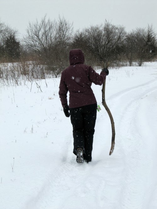 Woman dressed in black with a walking stick walking in the snow