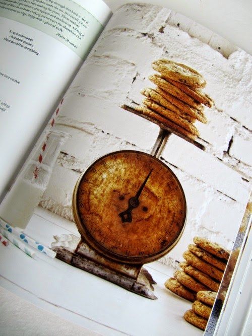 Open book with a photo of a vintage scale and piles of chocolate chip cookies. 