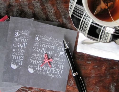 christmas cards and a pen with a cup of hot tea. 