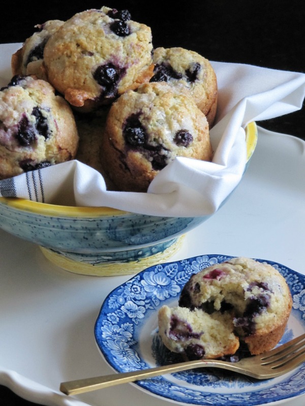 blueberry-muffins on blue and white plate with pottery bowl of muffins
