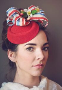 Kentucky Derby hat, woman wearing a red fascinator with red, white and blue ribbon. 