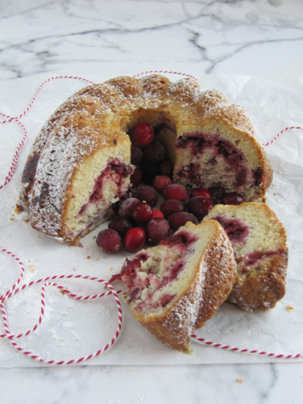 cranberry swirl bundt cake with 2 slices on a marble counter.