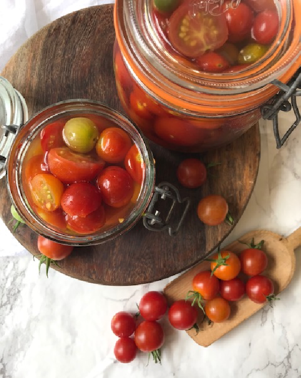Two clear jars filled with colorful cherry tomatoes. 