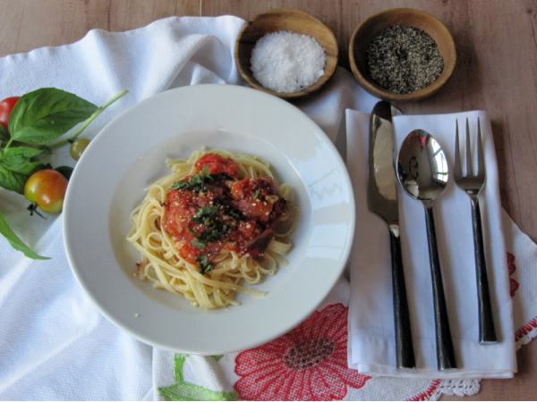 a while bowl filled with pasta topped with tomato sauce.