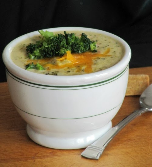 Broccoli cheddar soup in a white bowl with green stripes.