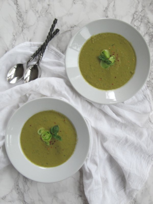 Roasted green tomato and basil soup in 2 white bowls. 