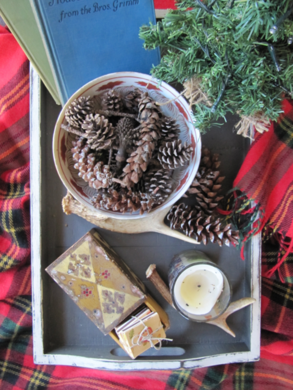 a distressed tray with a small christmas tree a bowl of pinecones and some antlers
