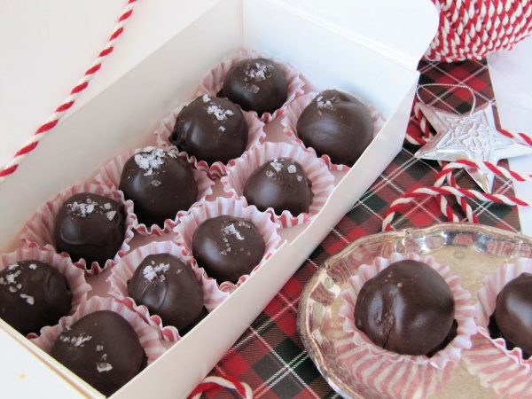 Fleur de sea chocolate truffles in a white box on a plaid piece of paper. 