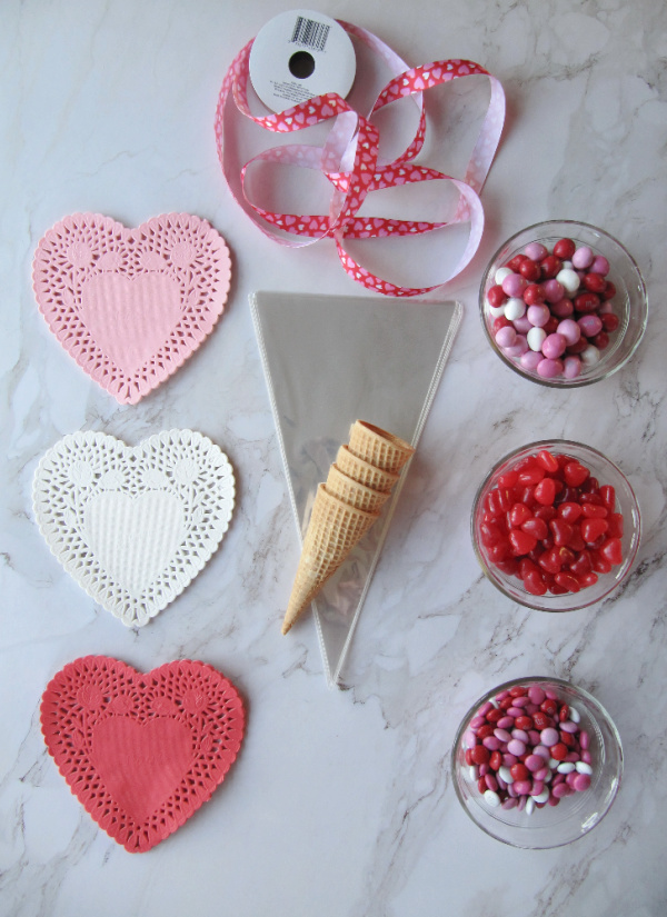 Red, white, pink heart doilies and three bowls of valentines day candy