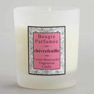 A white candle with a pink label