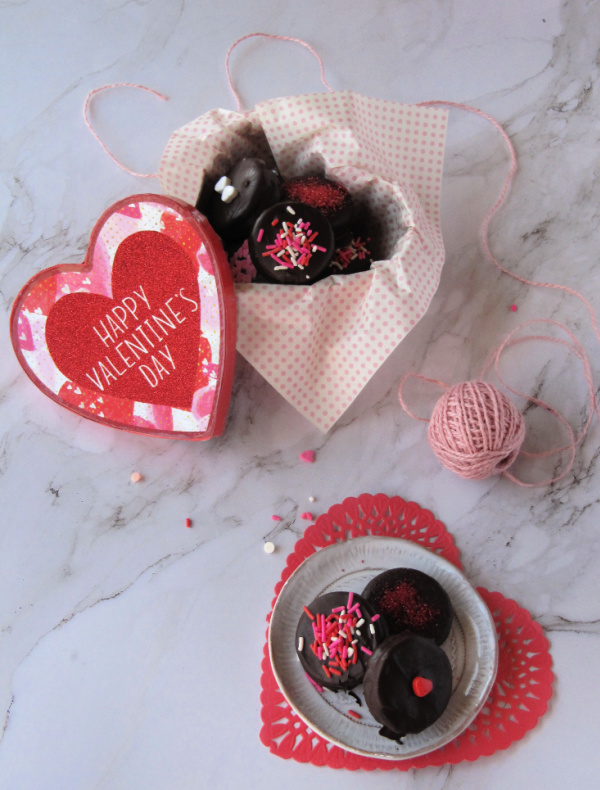 Heart shaped bow filled with chocolate covered Oreo cookies decorated with sprinkles