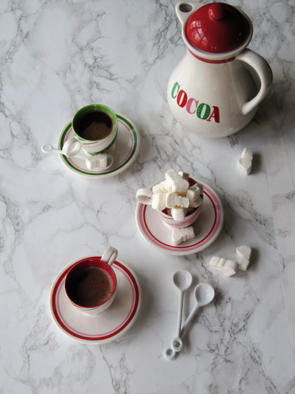 hot cocoa pot and three cups of cocoa with marshmallows 