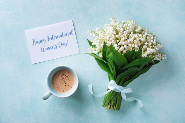 Lily of the valley with a cup of coffee and a sign on blue background