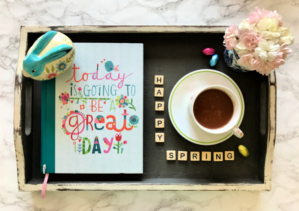 A book a bunny and a cup of cocoa on a tray that says happy spring