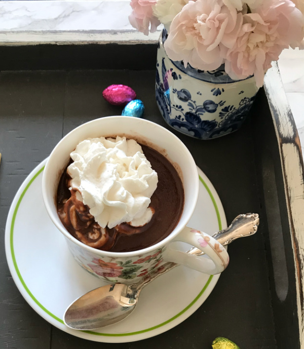 hot chocolate with whipped cream and a small vase of flowers
