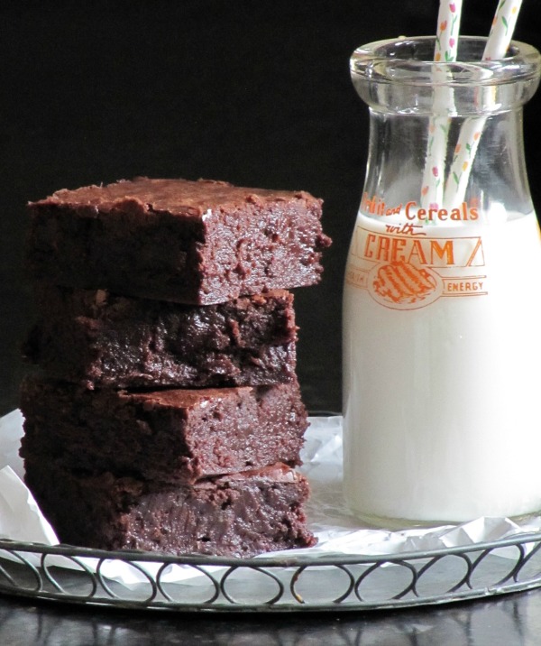 brownies sitting next to a milk bottle with two straws