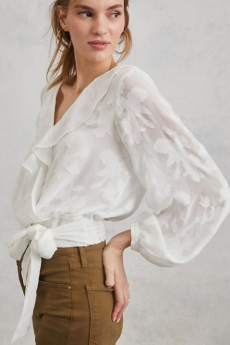 blond haired woman wearing a white blouse that ties at the waist and a tan pair of jeans