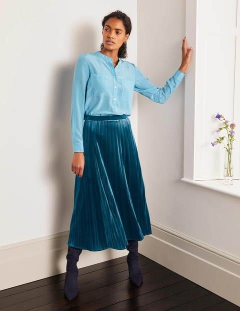 lady leaning against a wall wearing a teal green velvet skirt and top