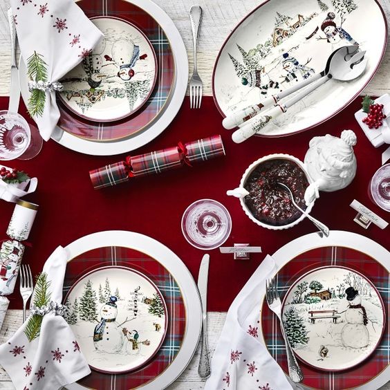 burgundy table with plaid plates topped with white snowman plates party poppers and christmas decor
