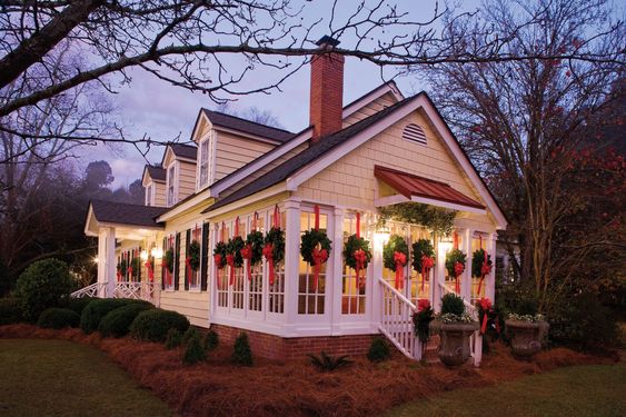 Small White House with a Christmas wreath on every window, front door decorations for christmas. 