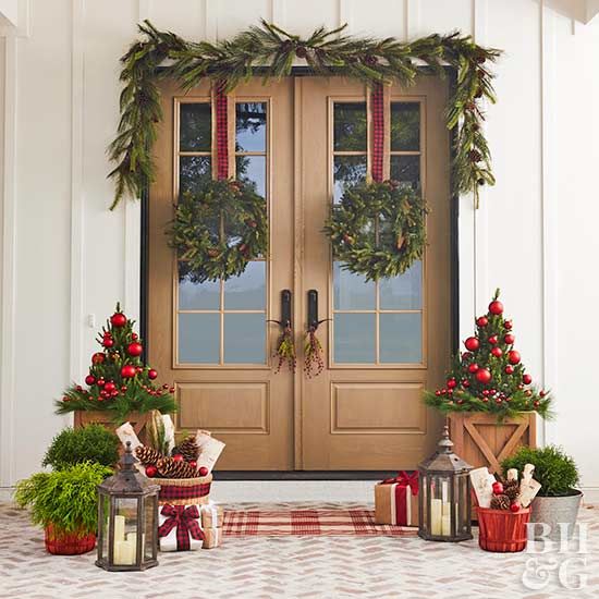 White House with a set of brown wood doors with two wreaths and small Christmas trees and presents next to the doors