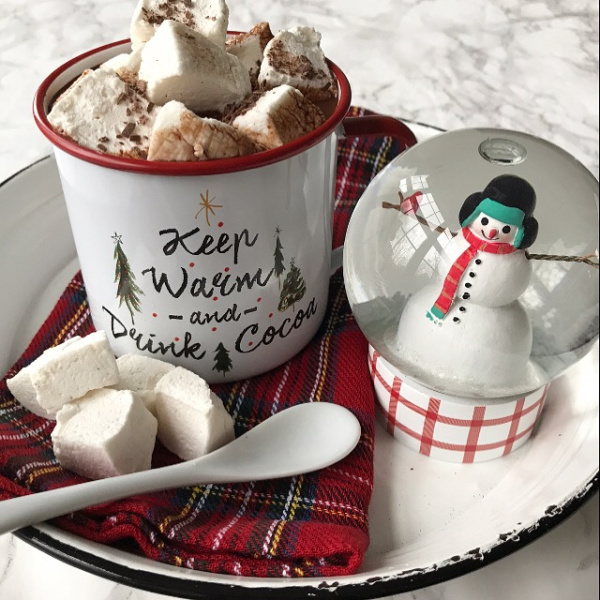 Cup of hot chocolate topped with marshmallows and a snow globe