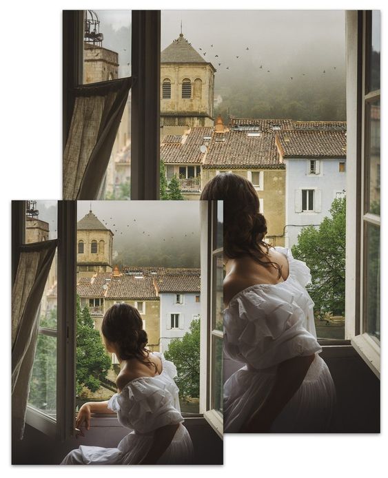 Woman in a white dress with her back to the carmera sitting in a window with a view of Provence in the background