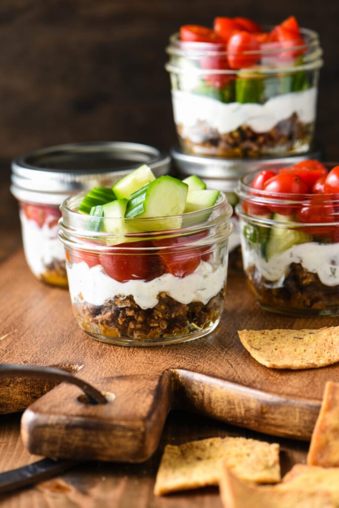 Greek layer dip in small jars on a cutting boars