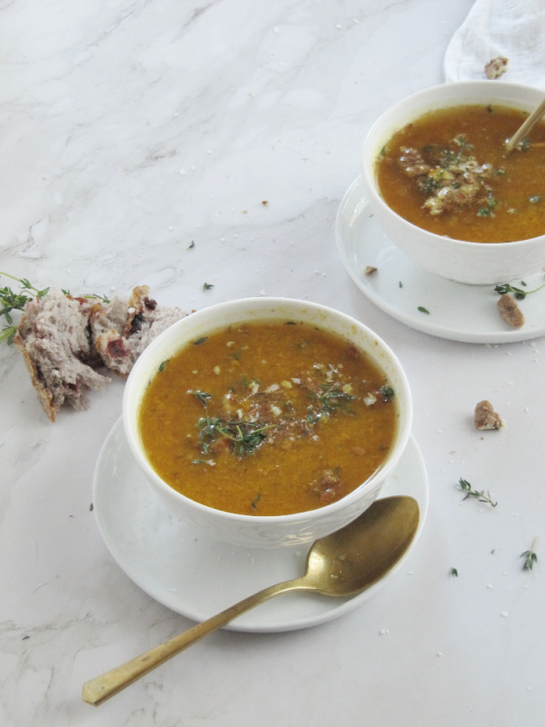 easy roasted butternut squash pumpkin soup in white bowls sitting on a brown cutting board with a white cloth in the right hand corner and a small bowl of pecans