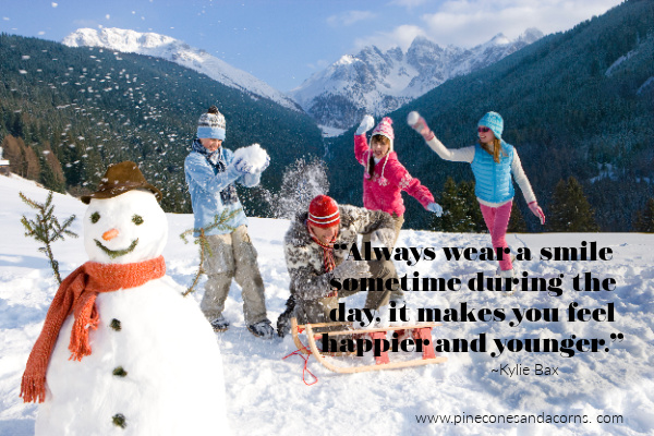 family on a hill in the snow having a snowball fight and a snowman in the foreground
