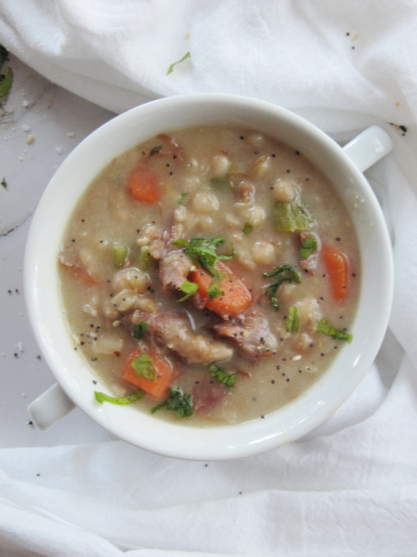 white bowl with two handles filled with ham and bean soup