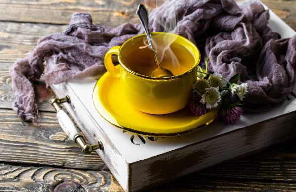 5 Easy Ways to Drink More Water, yellow cup and saucer of tea on a white box with a purple scarf