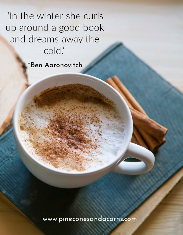 “In the winter she curls up around a good book and dreams away the cold.” cup of hot chocolate on a green book