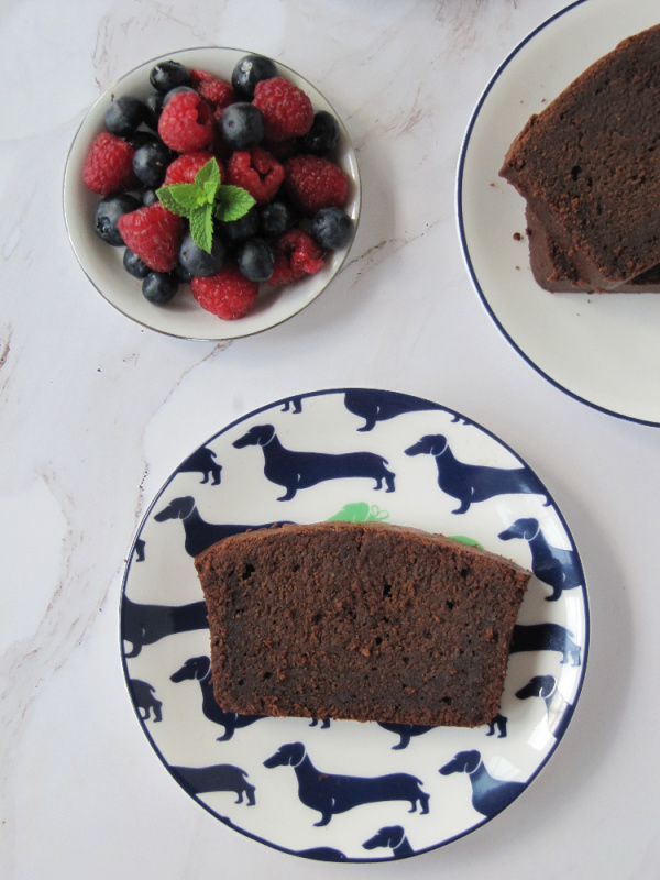 chocolate loaf cake on a white plate with blue dachshund