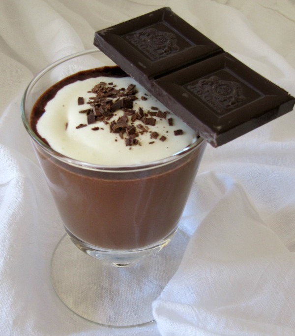 chocolate-atole drink in a glass with whipped cream and a bar of chocolate