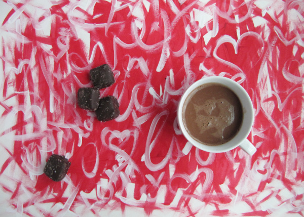 cup of hot chocolate and three caramels on a red and white abstract painting