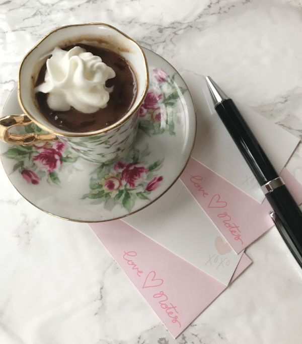 Homemade drinking chocolate in a white flower cup with whipped cream.