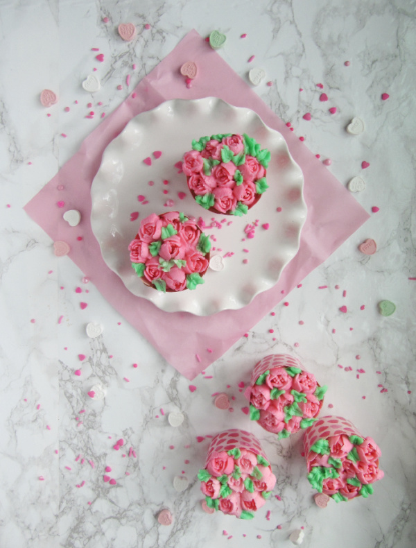 pink flower cupcakes on a white plate white almond cupcakes with best ever buttercream frosting.