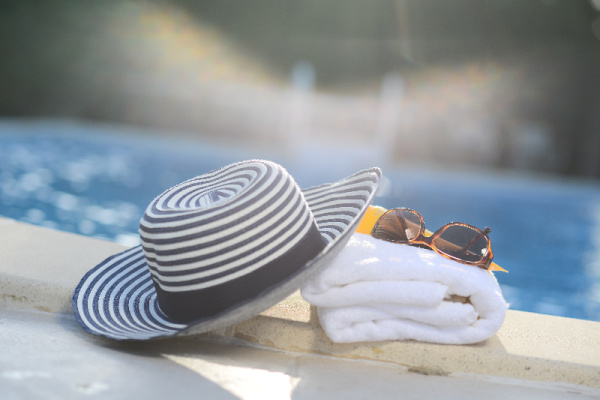 It'd ok to take a break beach hat towel and glasses by the poo