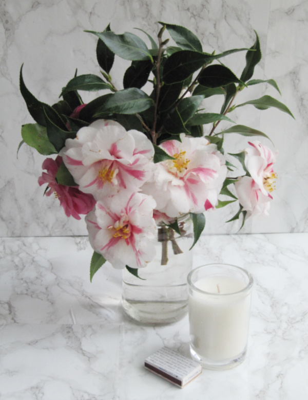camellia flowers in a vase with a white candle and matches