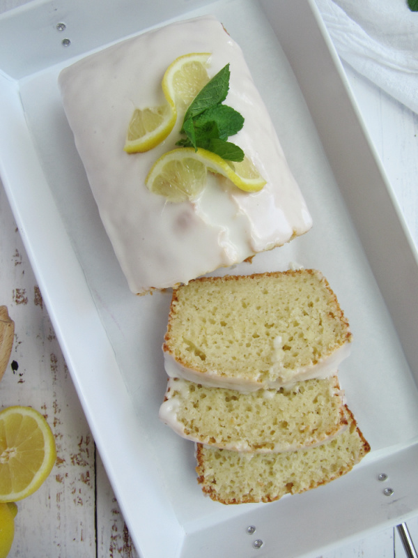 lemon loaf cake with lemon drizzle glaze in white enamelware tray