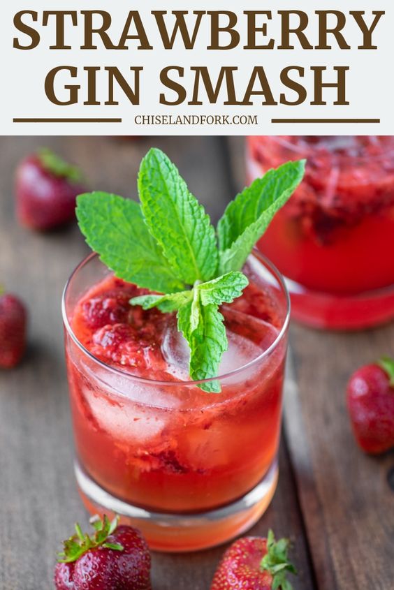 Friday Favorites 2 glasses Strawberry Gin Smash on a wood background with scattered strawberries