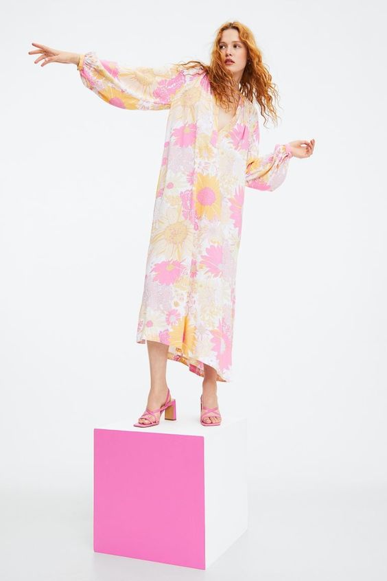 friday favorites woman wearing a pink and yellow dress standing on a pink box