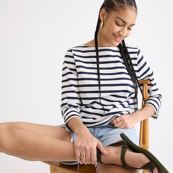 Monday musings woman sitting on a chair in a white and blue striped chair and jean shorts