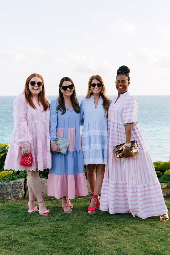4 women in pink and blue dresses posed alongside the waters edge