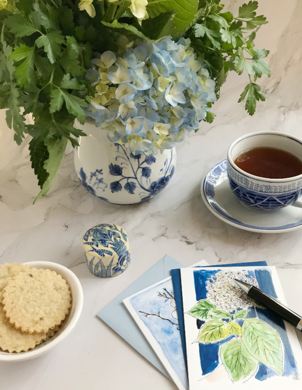 lavender lemon shortbread cookies in a bowl with a blue and white chinoiserie vase filled with flowers and a cup of tea