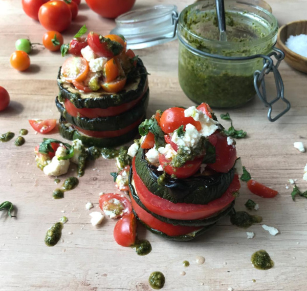 tomato zucchini stack salad with a jar of pesto.