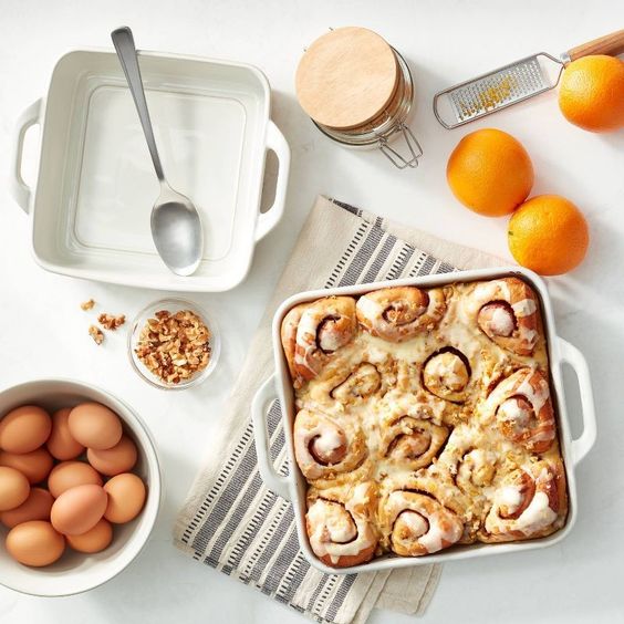 weekend meander gins two white square baking pans one with cinnamon rolls on a table with oranges and eggs
