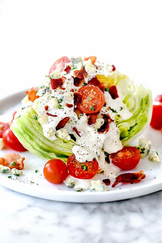 white plate with a edge salad tomatoes and bacon and blue cheese dressing